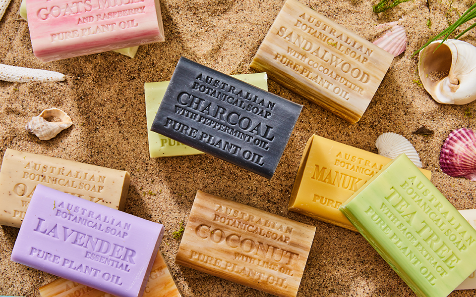 A variety of Australian Botanical Soap bars on a beach with shells.