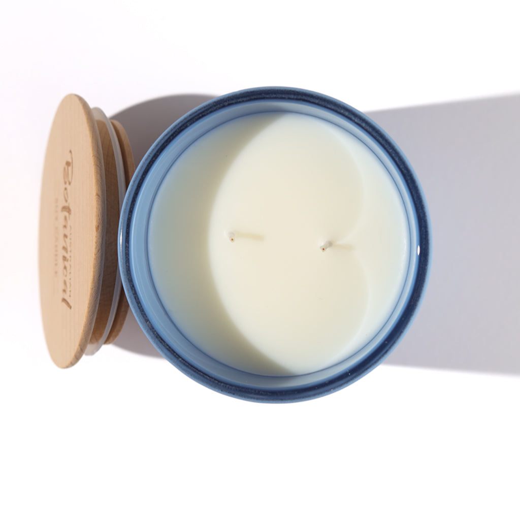 Candle in a glass jar with a wooden lid on a white background