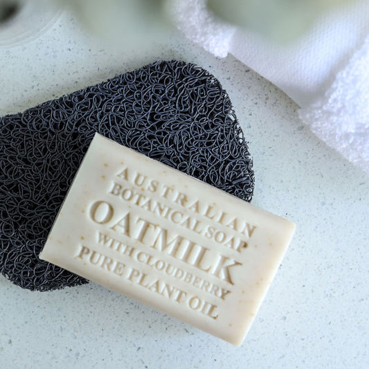 Bar of Australian Botanicals Oatmilk soap with a black scrubber on a light background