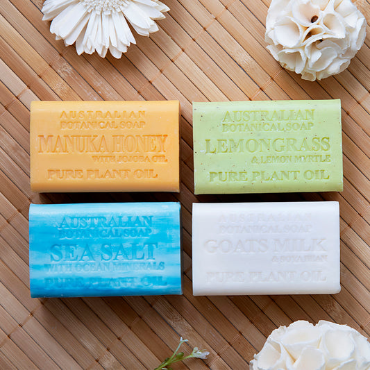 Four Australian botanical soap bars on a wooden surface with flowers.