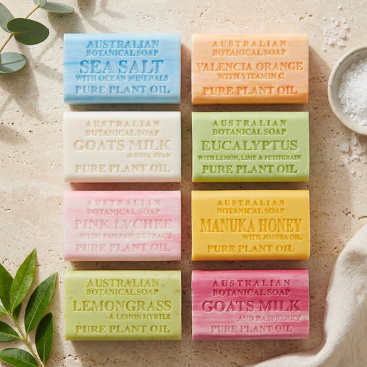 Assorted Australian botanical soaps on a textured surface with leaves and a bowl of salt.