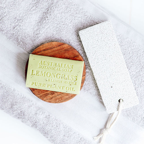 Lemongrass soap on a wooden disc with a towel and washcloth in the background