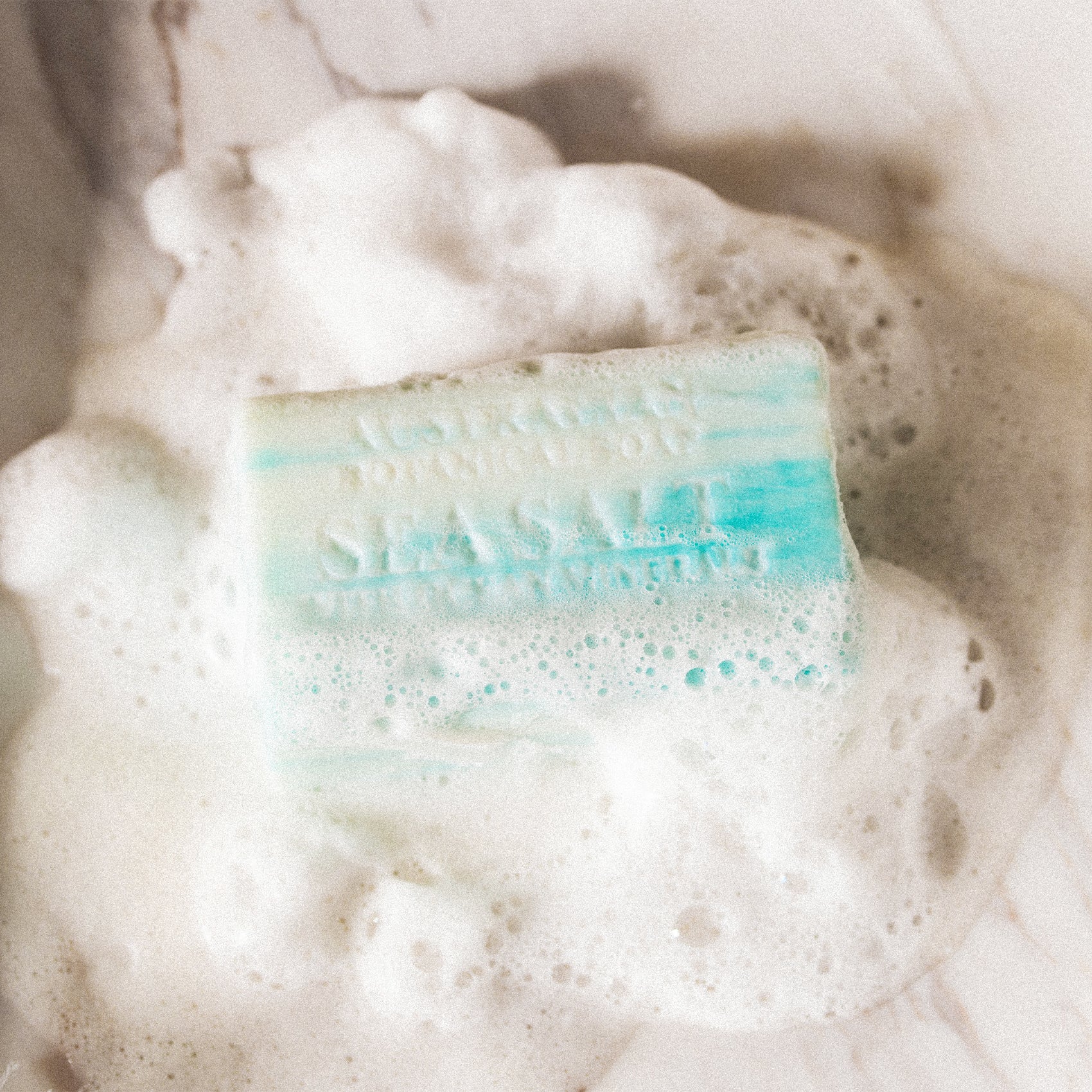 Bar of soap with a blue stripe in a bowl of sudsy water