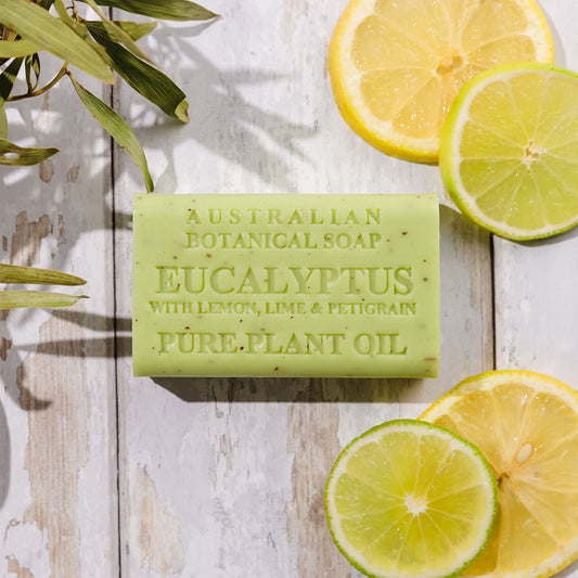 Bar of Australian Botanical Soap with Eucalyptus, Lemongrass, Lime & Peppermint on a wooden surface with lemon and lime slices.