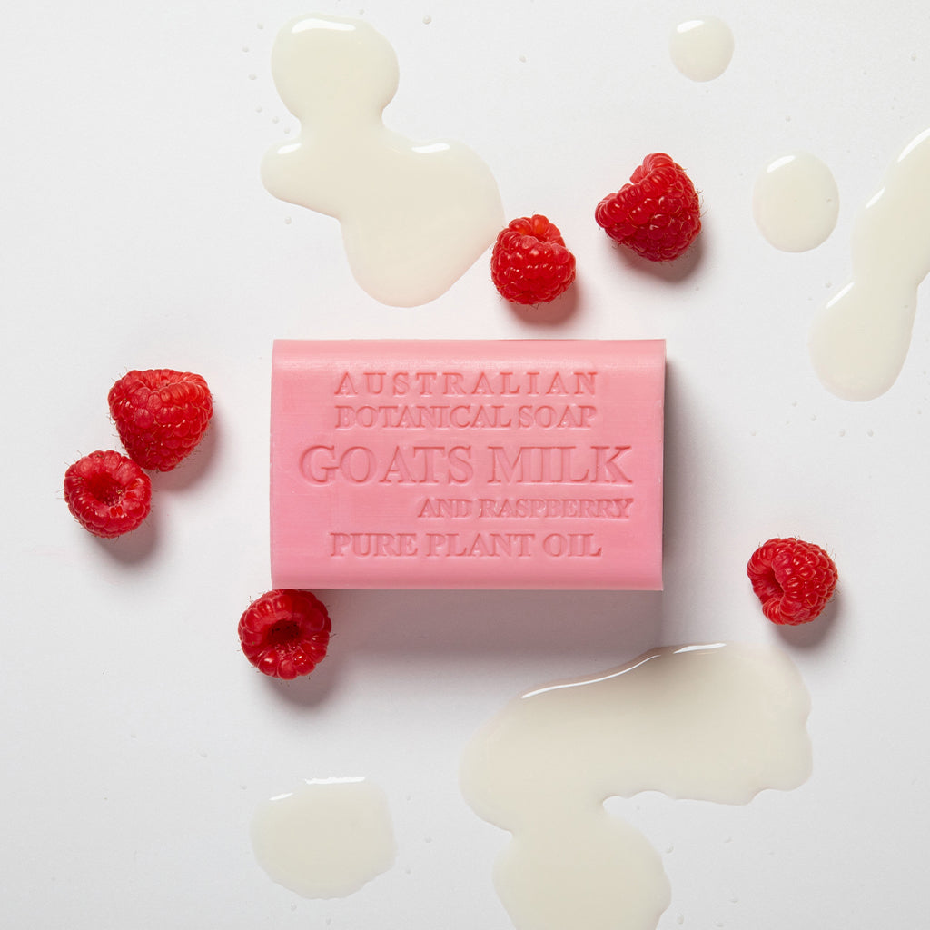 Pink bar of soap with raspberry and goat's milk ingredients on a white background