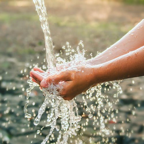 Hand catching water from a natural spring with a blurred natural background