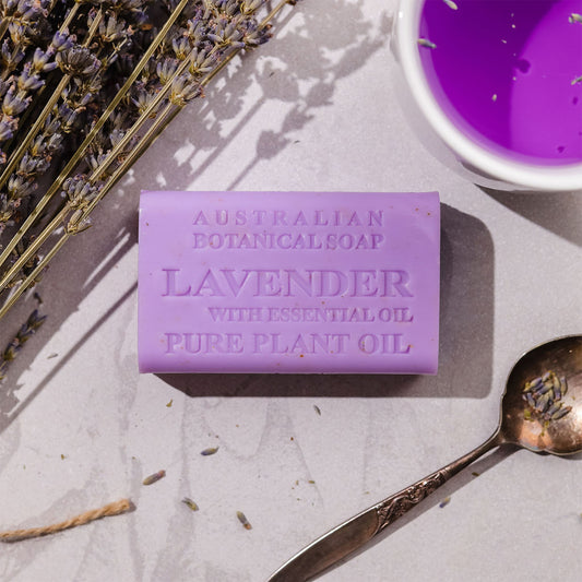 Purple lavender soap bar with a spoon and lavender flowers on a light surface