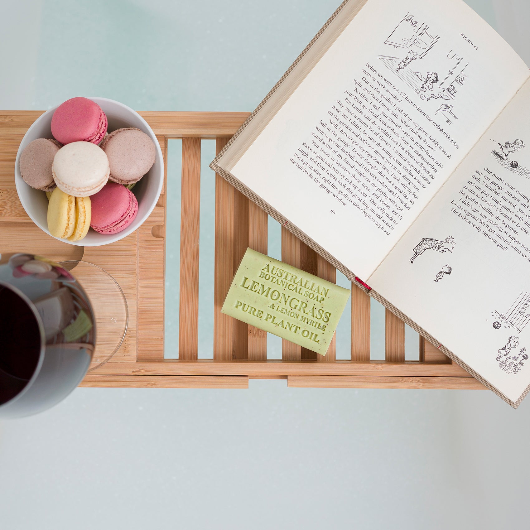 Open book with a bowl of macarons and a mug on a wooden tray with Lemongrass soap bar.