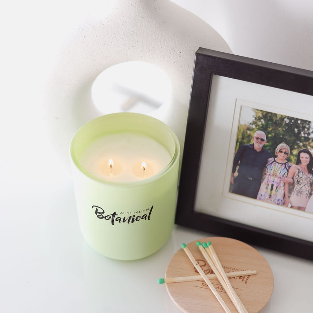 Green candle labeled 'Botanical' with matches and a family photo in the background