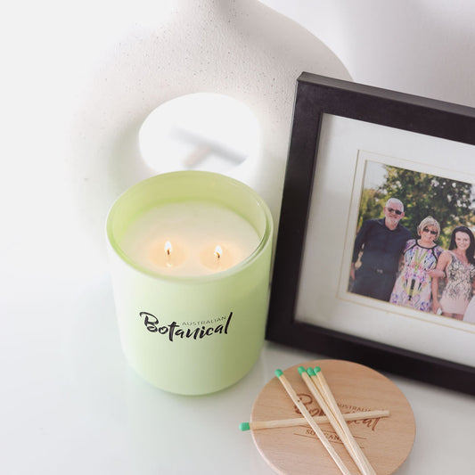 Green candle labeled 'Botanical' with matches and a family photo in the background