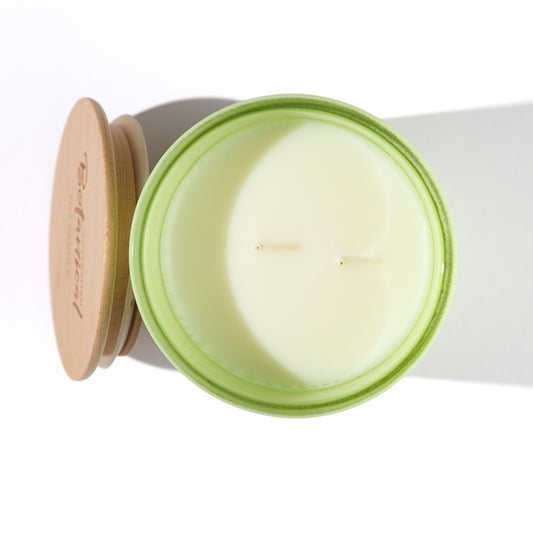 Candle in a green container with a wooden lid on a white background