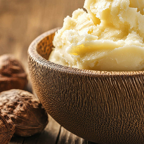 Wooden bowl filled with Shea butter  with Shea nuts on a wooden surface.