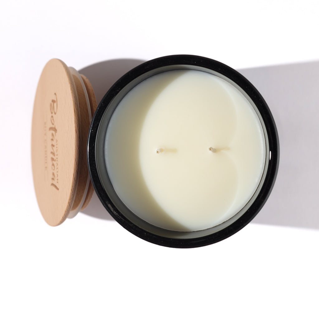 Candle in a black container with a wooden lid on a white background