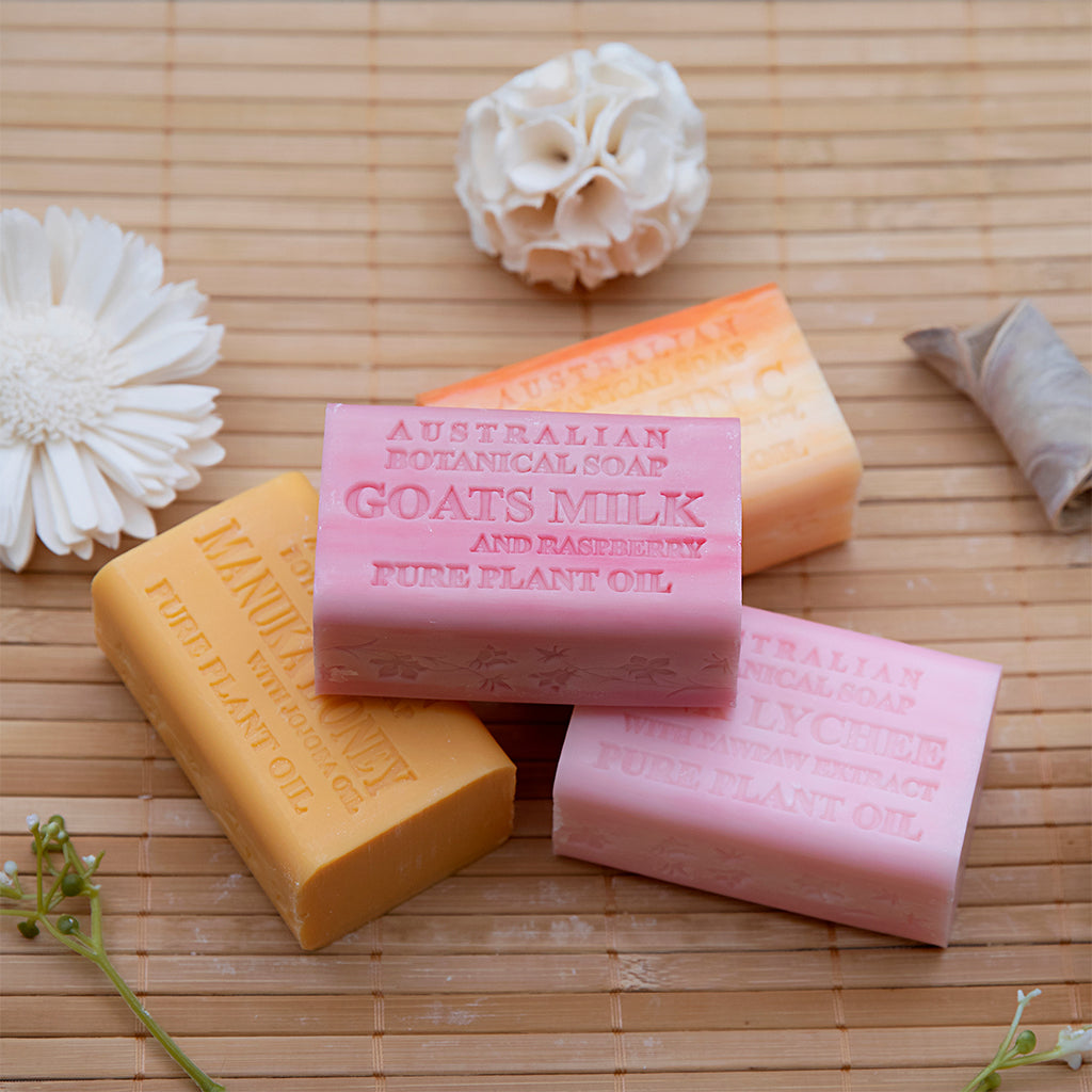 Four bars of soap on a wooden surface with decorative flowers.