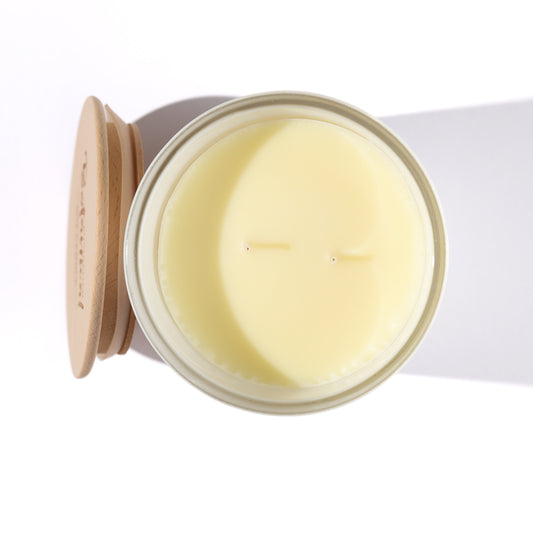 Open candle jar with a lit candle inside on a white background