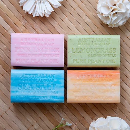 Four bars of Australian Botanical Soap on a wooden surface with flowers.