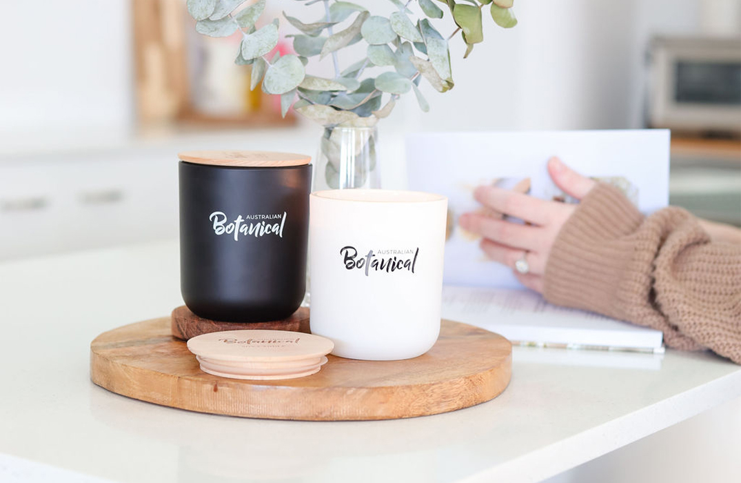 Sweet Sandalwood and Vanilla Caramel Soy Candles on counter with eucalyptus